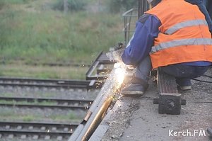 В Керчи на Горьковском мосту под дождем рабочие устанавливают забор